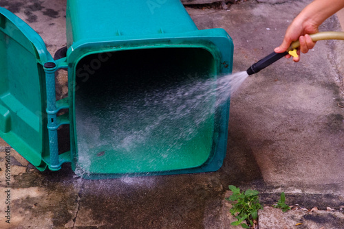 Cleaning the trash can with a water hose
