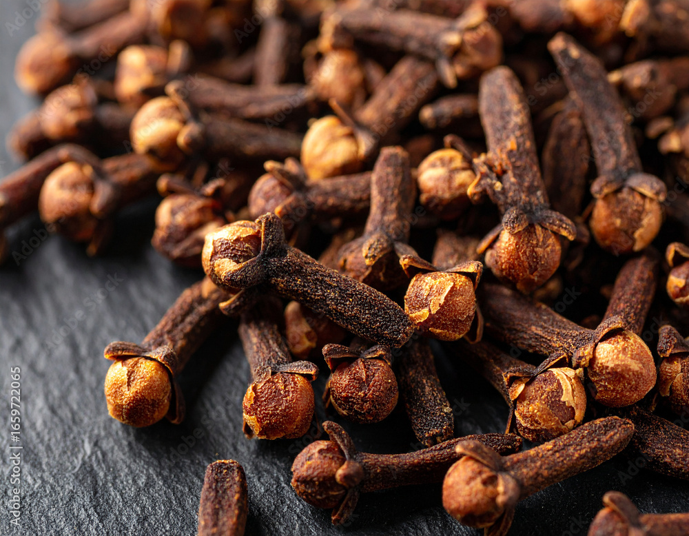 Fototapeta premium Dried cloves scattered on dark slate background, aromatic spice photography, macro detail texture