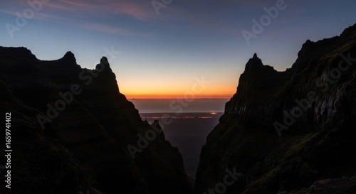 A dramatic sunrise illuminates a mountain pass, casting shadows on the rugged terrain.