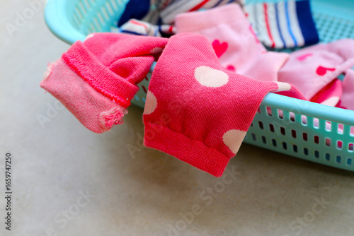 Colorful socks with heart and stripe patterns in a laundry basket.