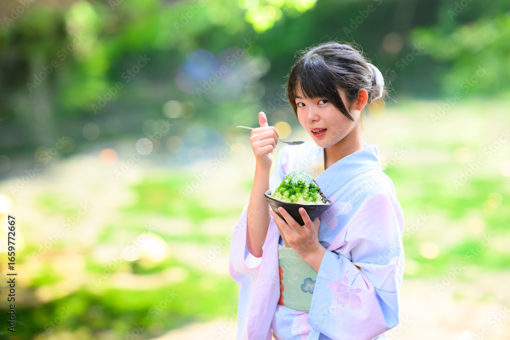 Obraz premium 夏の高原の湖で浴衣を着た日本人の小学生の女の子がかき氷を食べている風景