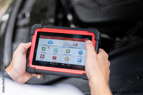 Obraz na plátně Modern technology in auto repair – mechanic using electronic car diagnostic tool