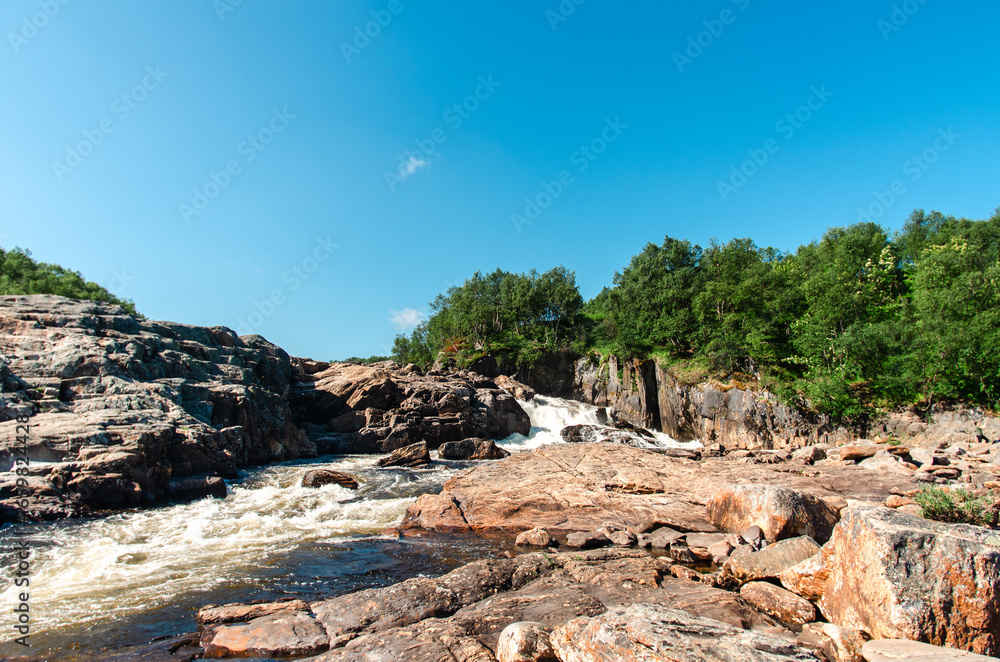 Naklejka premium streams of clear waterfall water and stone banks of a mountain river