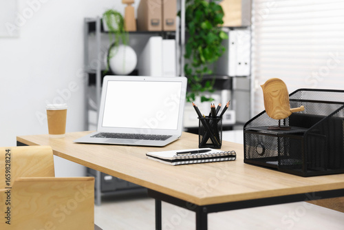Stylish workplace with laptop  coffee and stationery on wooden table in office  closeup