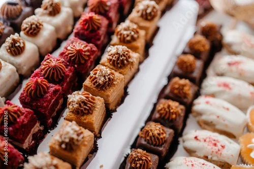 Obraz  z motywem Close-up of assorted gourmet mini pastries with colorful toppings arranged on a tray.