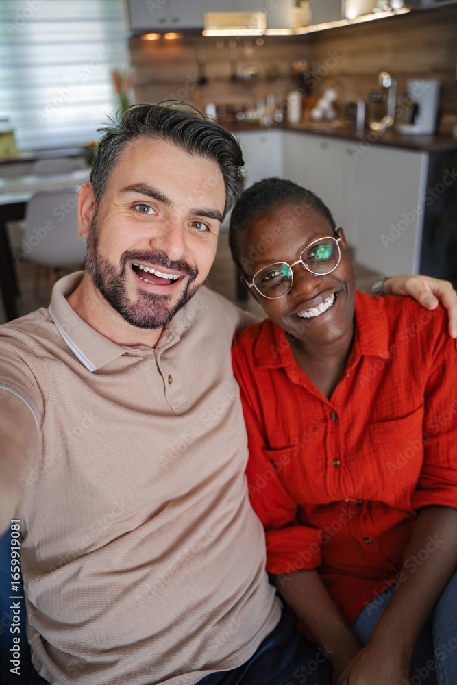 Fototapeta premium Happy multi-ethnic couple taking a selfie at home