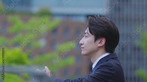ビルを背景に遠くを見つめるスーツを着た日本人ビジネスマンの男性	