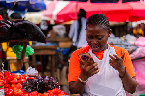 Young, African market woman making a phone call with her smartphone