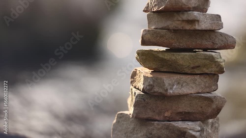 Stacked Rocks Near River Tilt Up With Background Blurred