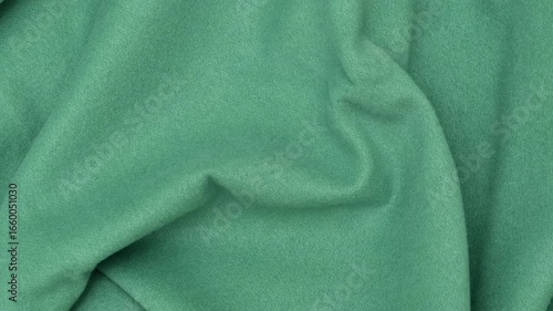 Green cloth texture with soft folds. Green fabric background of soft and smooth textile material. Fabric texture for design and decoration. Top view.