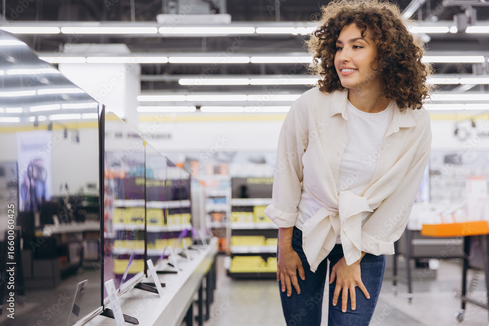 Fototapeta premium Woman choosing new television in electronics store