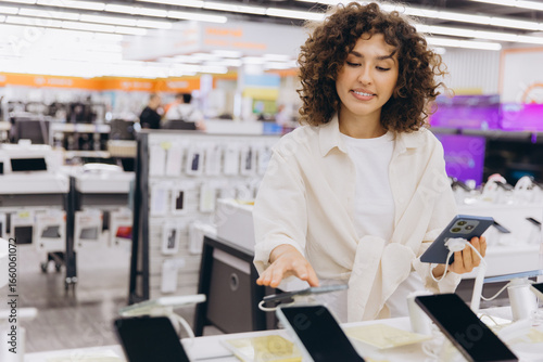 Tableau sur toile Woman comparing smartphones in electronics store