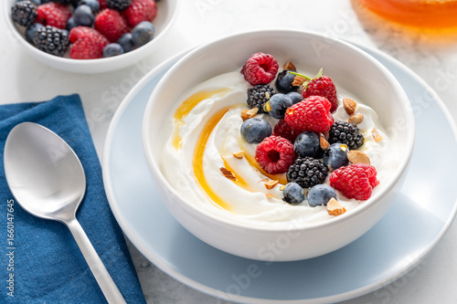 Greek yogurt bowl with raspberries, blueberries, blackberries, almonds and honey for breakfast. Healthy tasty snack. Selective focus
