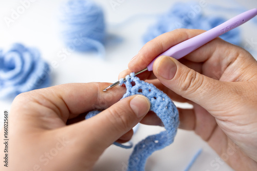 Close up of hands crocheting with blue yarn and hook
