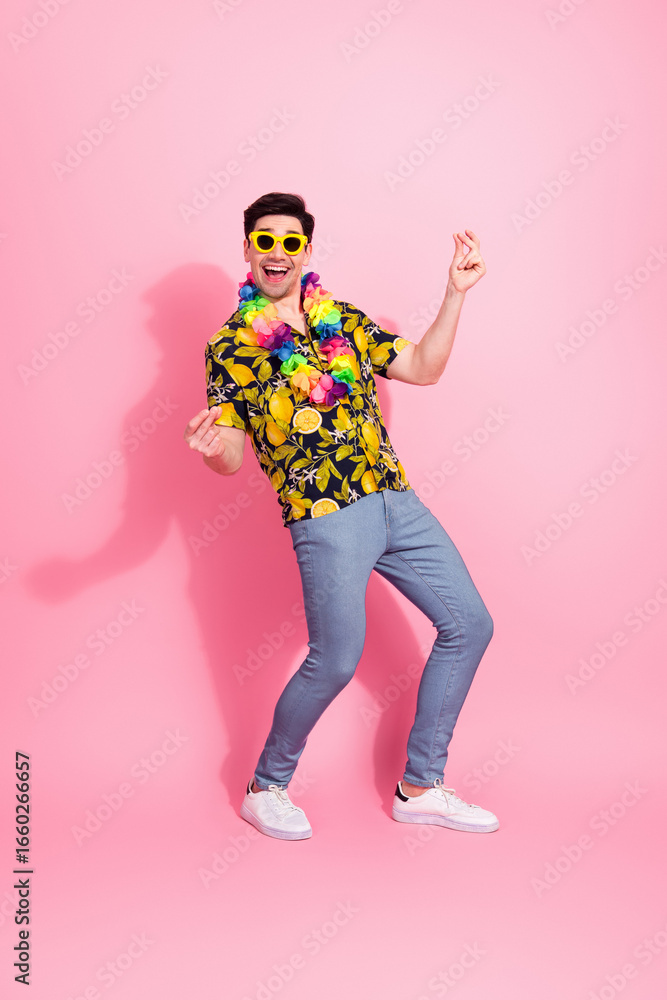 Fototapeta premium Young cheerful man in vibrant floral shirt and sunglass enjoying a good mood against a bright pink background