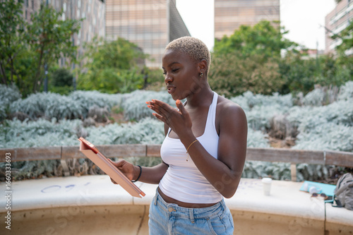 Obraz na plátně Young woman gesturing while reading a script in a park