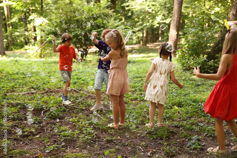 Obraz premium Cute little kids having fun with soap bubbles in park