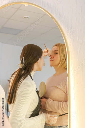 reflection in the mirror of the work of the permanent makeup artist on the formation of the lip contour