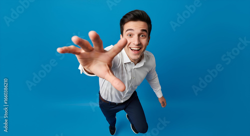 Excited young man reaching hand forward to grab something. Happy businessman offering a helping hand or taking something. Man's hand reaching out for help, connection, or opportunity.
