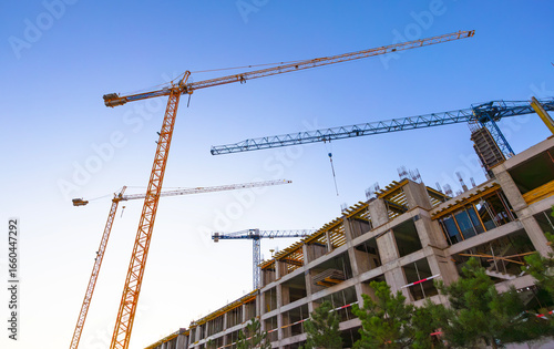 Construction of a new residential area using high-rise cranes at sunset.