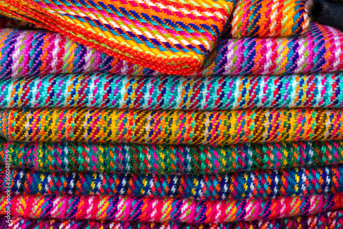 Traditional handmade ecuadorian textiles and fabrics, Otavalo market, Ecuador. Focus on stack of textiles.