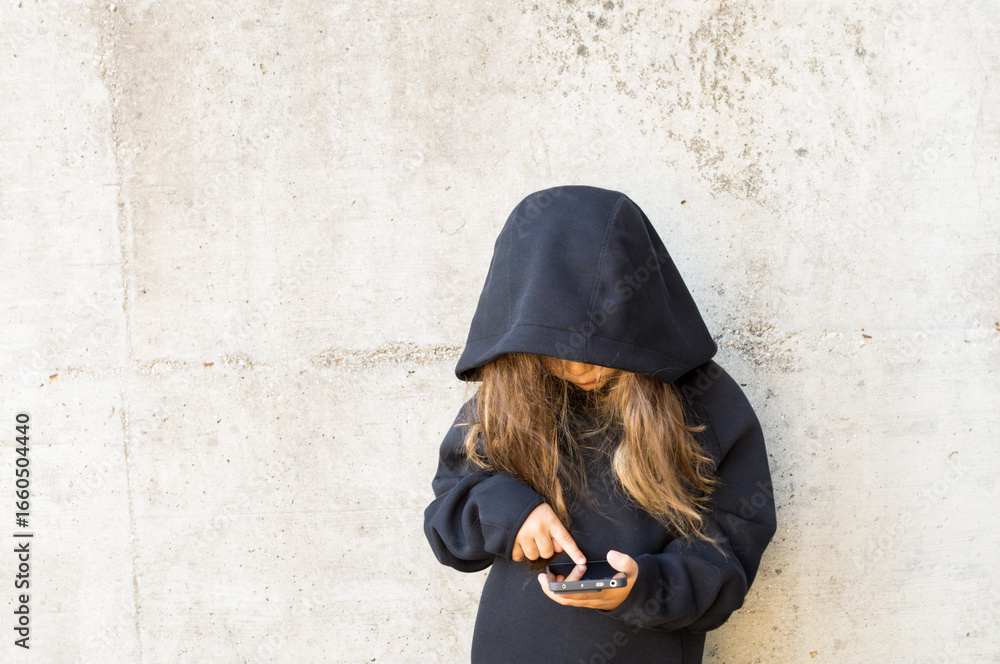 Naklejka premium Teenager in front of a gray wall with a cell phone