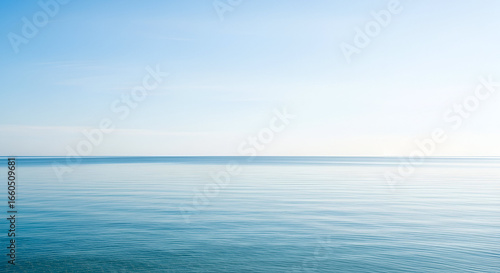 A wide-angle shot of calm blue ocean meeting a clear bright sky, minimalist composition, neat horizon line, clean natural background.