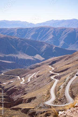 Empty desert highway stretches into hazy mountains under a clear sky