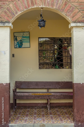 An old pew behind the arched entrance, with a window with Christmas decoration, in a vintage house at the town of Sora, in the eastern Andean mountains of central Colombia.