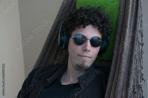 Obraz na płótnie Young man wearing sunglasses lying and relaxing in a hammock.