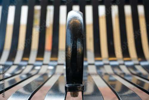 Foto Artistic close-up of a black metal bench armrest with curved slats in shallow depth of field, creating an abstract urban design pattern
