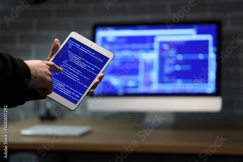 Hacker using tablet computer in dark room, closeup