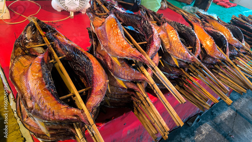 Traditional smoked fish, known as fufu fish, displayed on bamboo skewers at a market in North Halmahera. Authentic local cuisine and Indonesian food culture.