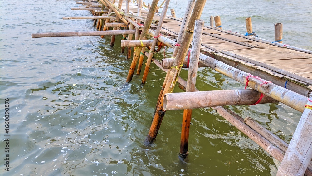 Fototapeta premium Traditional bamboo bridge stretching over the sea, serving as fishing spot and rustic dock