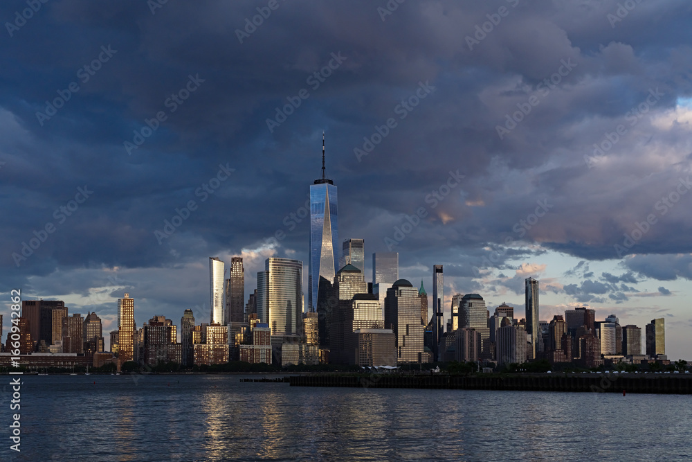 Obraz premium New York city. NYC cityscape. Lower Manhattan and One World Trade Center in New York Cit. Skyscrapers of Manhattan located near rippling water of New York bay against blue sky. New York skyscrapers.