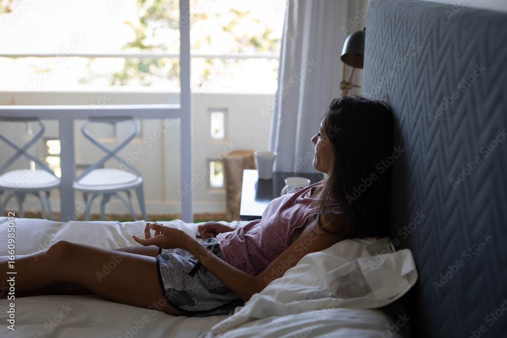Obraz premium White linens resting on queen bed against gray headboard near sliding door revealing balcony chairs