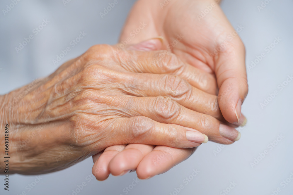 Fototapeta premium Gentle touch of a young hand holding an elderly wrinkled hand