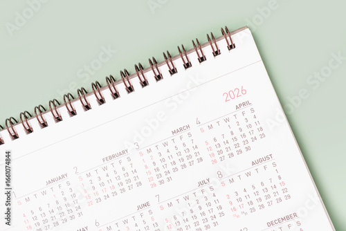 Paper calendar for 2026 on green background close-up top view.