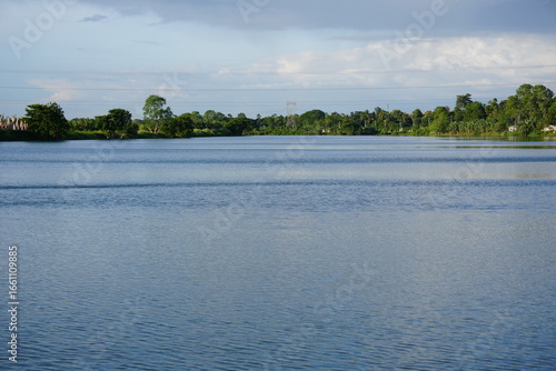A body of water of a large lake, with trees and foliage lining the distant shore
