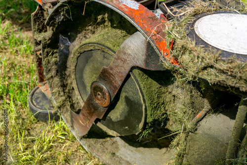 Foto Dirty lawn mower blade covered with grass residues, detailed close-up of cutting