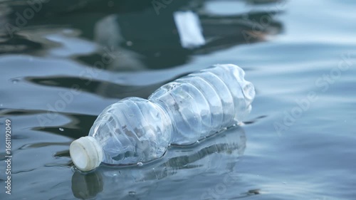 A bottle of water is floating in the water. The bottle is empty and has a plastic cap. The bottle is floating in the water, and it is a reminder of the importance of recycling and reducing waste