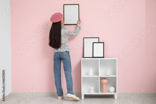 Young woman hanging picture...