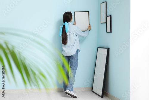 Young woman hanging picture...