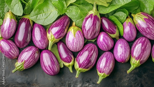 Freshly Harvested Purple Eggplants Alongside Leafy Greens on a Dark Surface