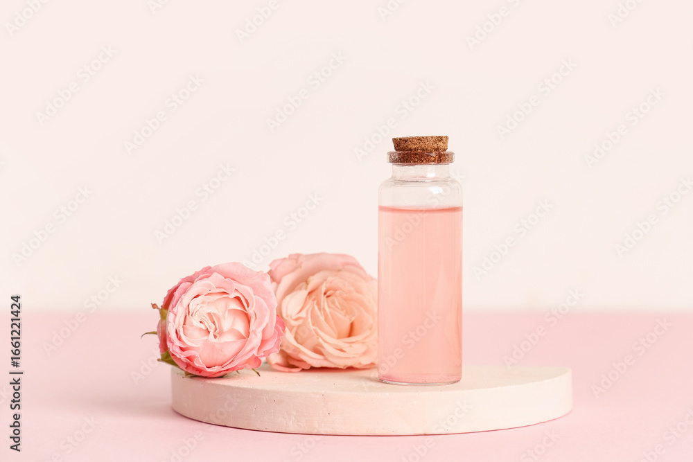 Bottle of cosmetic oil, roses and plaster stand on pink background Bottle of cosmetic oil, roses and plaster stand on pink background