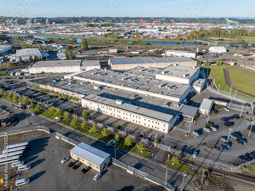 Tacoma, United States - 18 April 2025: Aerial view of the the Northwest Detention Center bathed in the soft glow of the afternoon sun, contrasting sharply with the distant cranes.