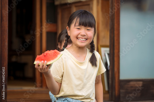 縁側でスイカを食べる女の子