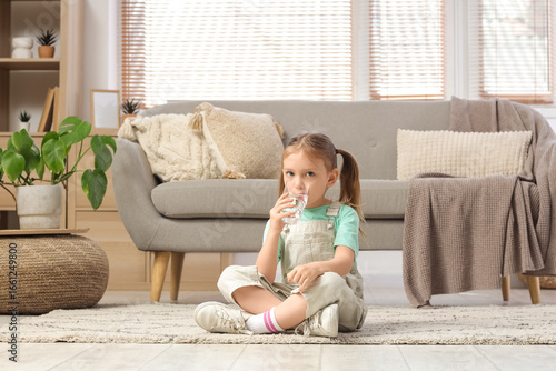 Cute little girl drinking w...