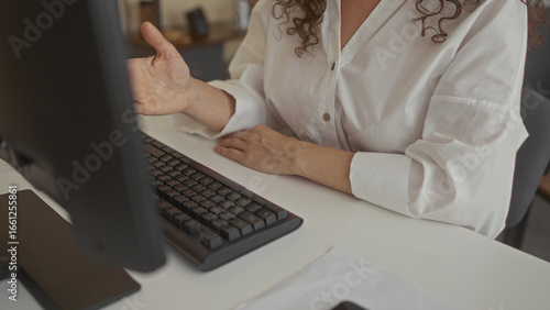 Woman typing on a slim keyboard with fingers poised on a white desk in an office building; efficiency productivity focus.