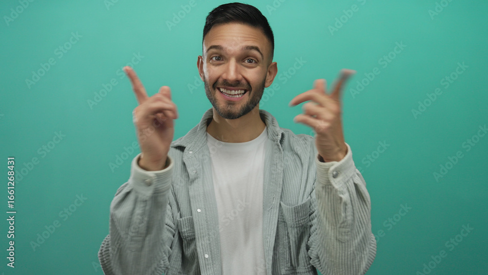 Fototapeta premium Young hispanic man pointing to his smile with both hands against a bright blue background, expressing happiness and confidence.